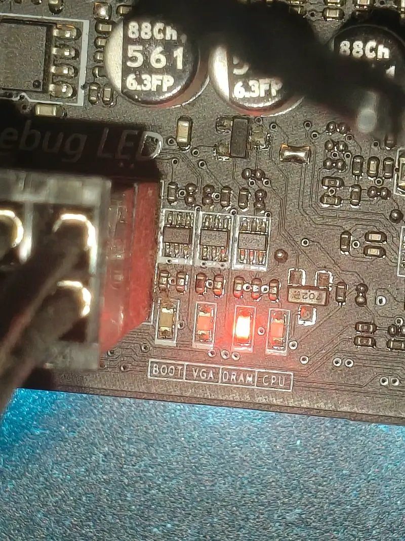 Primer plano de una placa base de sobremesa con los LED de diagnóstico BOOT, VGA, DRAM y CPU; el de DRAM está encendido en rojo